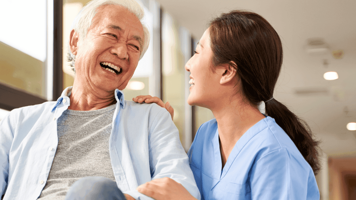 An elderly man laughing with a caregiver